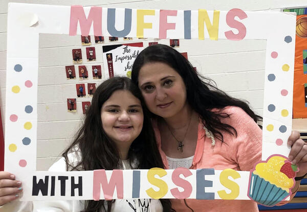 Mother and daughter pose with Muffins with Misses sign