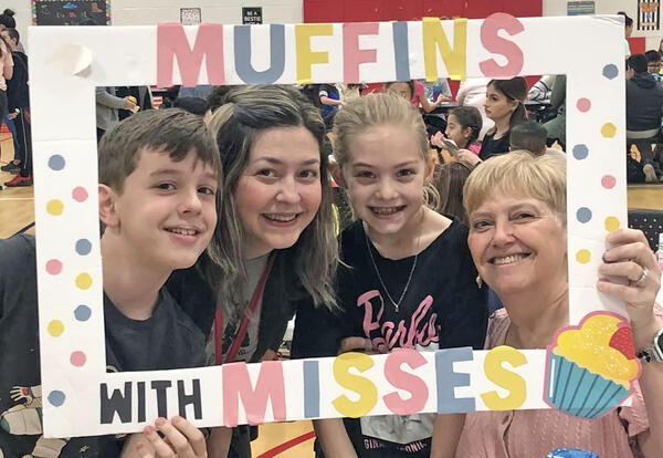 Mother and three children pose with Muffins with Misses sign