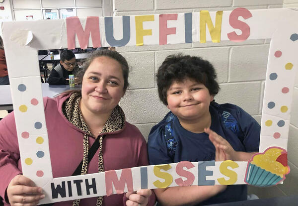Mother and son pose with Muffins with Misses sign