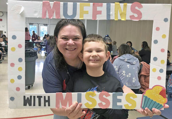 Mother and son pose with Muffins with Misses sign