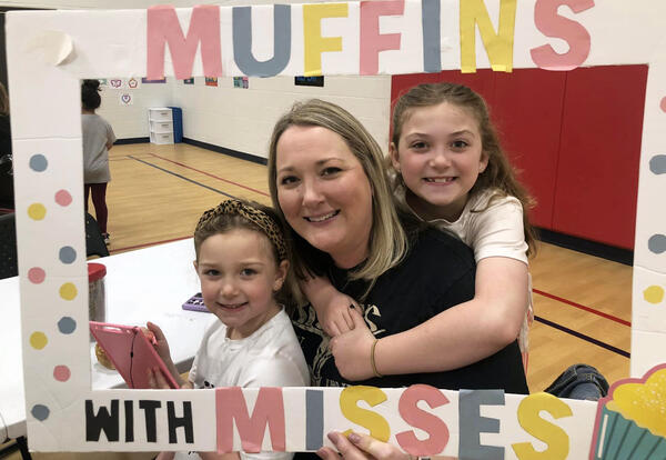 Mother and two daughters pose with Muffins with Misses sign