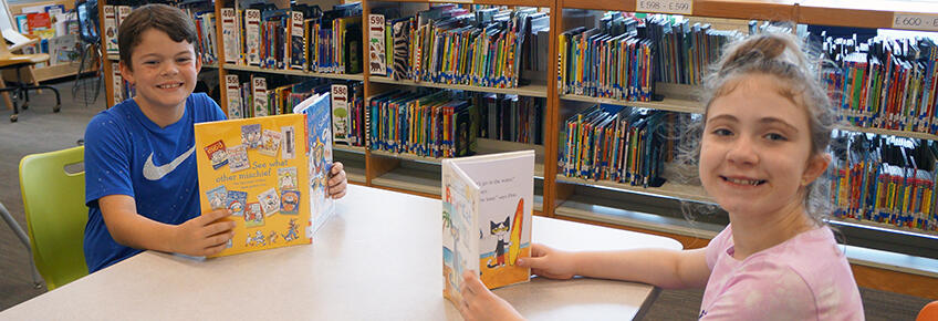 two students looking at books in media center