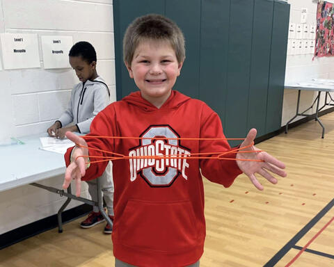 Student poses with string used to build dexterity in PE class