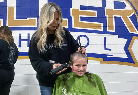 Student smiling while getting hair shaved at school St. Baldrick's event