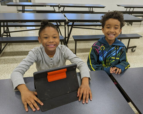 Two students smiling while working on iPad