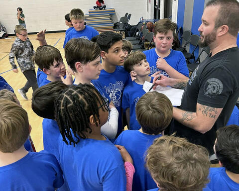 Fifth grade boys' basketball team huddled around listening to coach