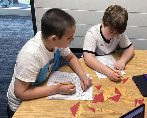 Two students working  together on the area of a triangle in math class