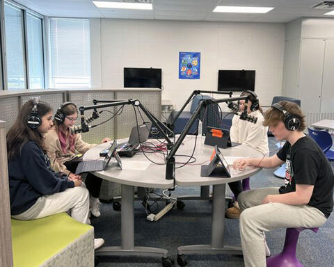 Four students creating a podcast in the school library