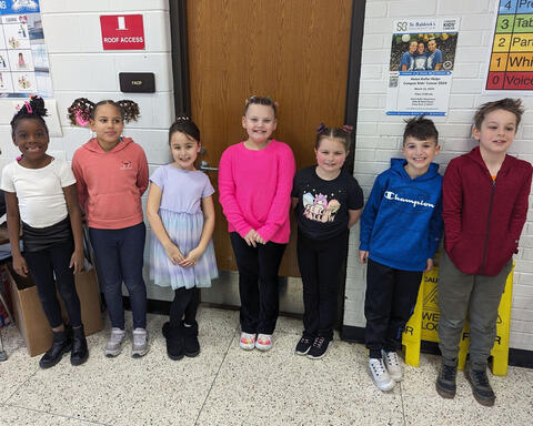 Smiling students proudly pose standing in school hallway